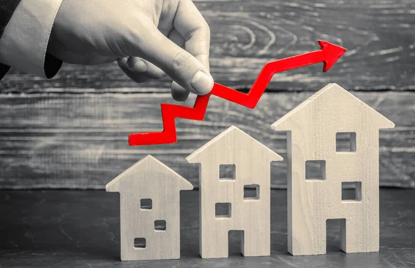 Wooden houses stand in a row from small to large with a red arrow up. concept of high demand for real estate. increase energy efficiency of housing. rise in house prices. property. population growth