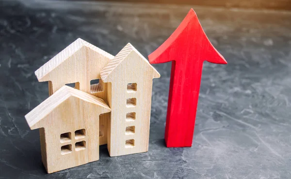 Wooden houses with a red arrow up. concept of high demand for real estate. increase energy efficiency of housing. rise in house prices. property. population growth. Increase in the real estate market