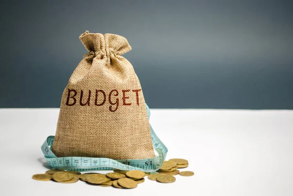 Bag with money and tape measure and the word budget. Limited budget. Lack of money. The concept of accumulating money in the family budget. Family Insurance. Distribution of cash savings. Saving money