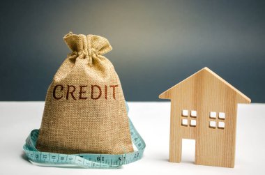 Para ve bir mezura ve kelime kredi ve ahşap bir ev ile bir çanta. Kredi ödemek için para eksikliği. Mortgage Konut için. Tasarruf ve para birikimi. Borç içinde Emlak. Yoksulluk