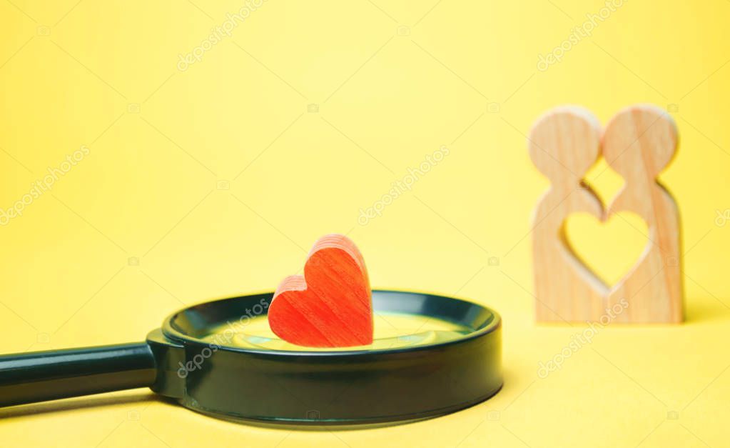 Heart, magnifying glass and a couple in love. The concept of family problems and loss of feelings for your loved one. Consultation family psychologist. Rupture / divorce. Recovery of the old feelings