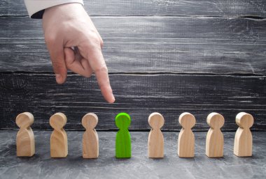 Bir işadamı el bir yeşil ahşap insan figürü için işaret eder. İşçiler, aratmak insan kaynakları yönetimi kavramı. İşe alma ve volnenie çalışanları, basınç, işçi hakları ihlali.