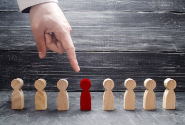 Bir işadamı el ahşap bir insan figürü için işaret eder. İşçiler, aratmak insan kaynakları yönetimi kavramı. İşe alma ve volnenie çalışanları, basınç, işçi hakları ihlali.
