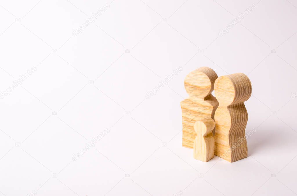 Wooden figurines of a young family on a white background. Concept of a young strong and healthy married couple. A loving couple expects the birth of a child. Pregnancy and planning the future family.