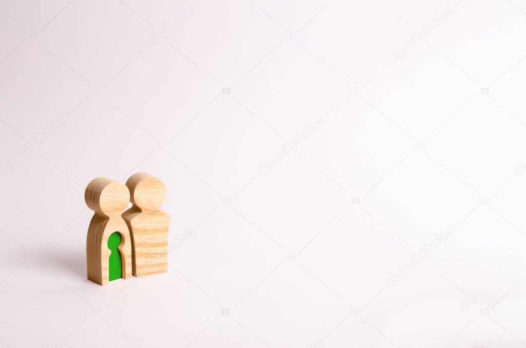 Wooden figurines of a young family on a white background. Concept of a young strong and healthy married couple. A loving couple expects the birth of a child. Pregnancy and planning the future family.