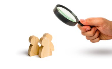 Büyüteç üç kişinin bir arada durup konuşmasına bakıyor. İnsanların üç ahşap figürleri beyaz bir arka plan üzerinde bir konuşma yapmak. İletişim, buluşma yeri. Seçici odaklama