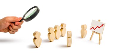 Magnifying glass is looking at the Wooden figures of people stand in the formation and listen to their leader. Business training, briefing and inspirational speech. Employee reports. Selective focus