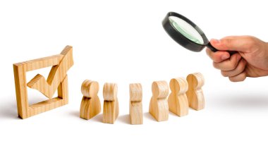 Büyüteç bir onay kutusunun yanındaki birlikte insan figürleri standında arıyor. seçimler ve sosyal teknolojileri kavramı. Gönüllüler, partiler, adaylar. Seçici odak