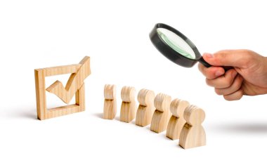 Büyüteç bir onay kutusunun yanındaki birlikte ahşap insan figürleri standında arıyor. Seçimler ve sosyal teknolojileri kavramı. Gönüllüler, partiler. Seçici odak