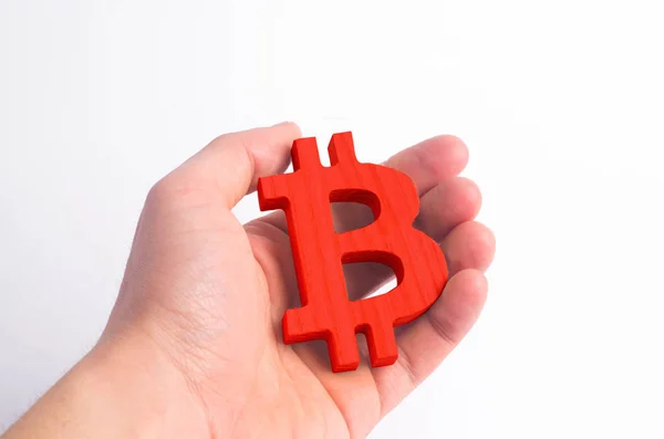 Hand holds a wooden Bitcoin on a white. Crypto currency, blocking technology. The collapse and rise in the cost of bitcoin. Mining farms, miners, stock exchange crypts. Decentralized money