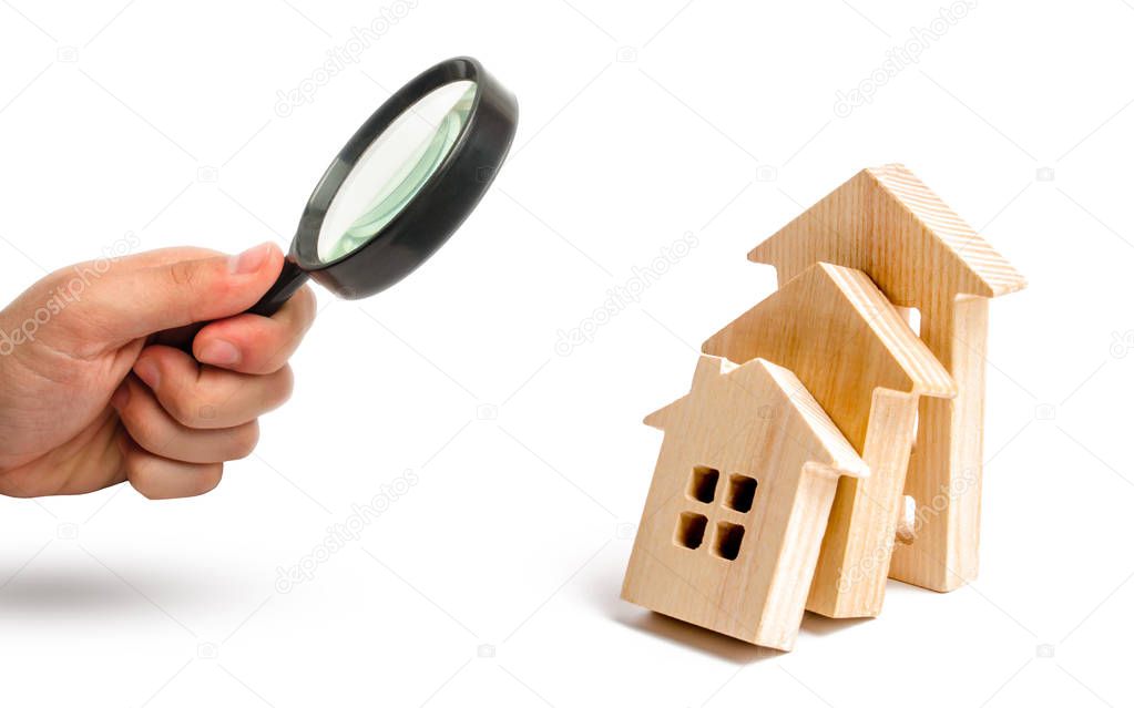 Magnifying glass is looking at the Wooden houses fall on each other like dominoes. concept of falling prices for house purchase and rent. violation of technology during construction Selective focus