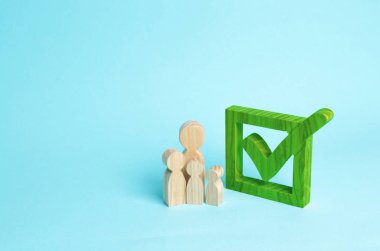 Üç ahşap insan figürleri birlikte bir onay kutusunun yanındaki bekletin. Seçimler ve sosyal teknolojileri kavramı. Gönüllüler, partiler, adaylar, seçim electorates. İnsan hakları.