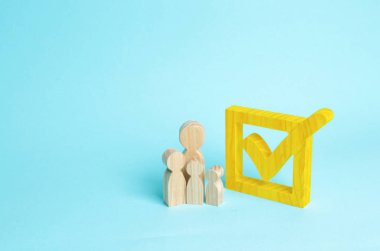 Üç ahşap insan figürleri birlikte bir onay kutusunun yanındaki bekletin. Seçimler ve sosyal teknolojileri kavramı. Gönüllüler, partiler, adaylar, seçim electorates. İnsan hakları.