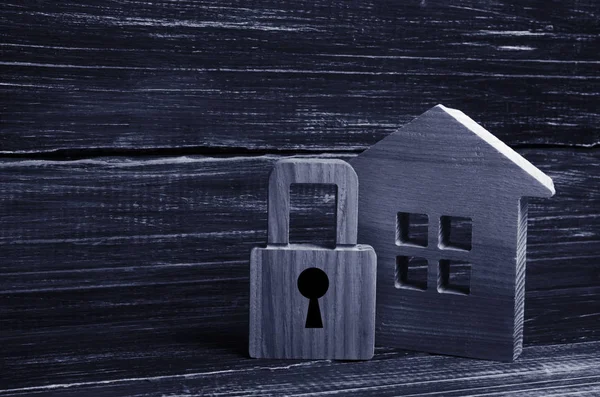 Wooden house with a padlock. House with a lock. Security and safety, collateral, loan for a mortgage. Confiscation of property for debts. Safety and alarm system. Buying a new home