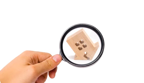 Magnifying glass is looking at the wooden house with a crack. The concept of a damaged house. Renovation, repair and restoration of the old building. Property insurance. Weather element. Damage. — Stock Image Magnifying Glass Looking Wooden House Crack Concept Damaged House Renovation Royalty Free Stock Images