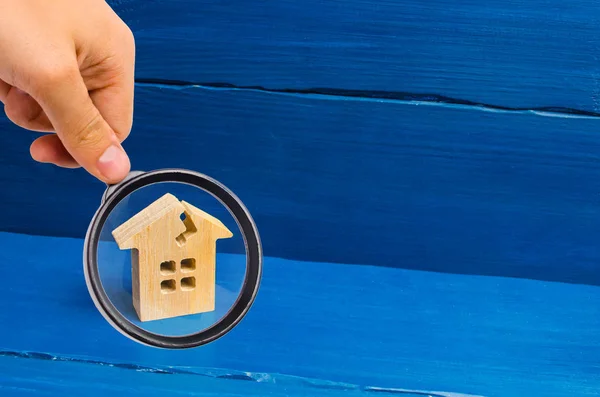 Magnifying glass is looking at the wooden house with a crack. The concept of a damaged house, dilapidated housing. Renovation, repair and restoration of the old building. Property insurance. — Stock Image Magnifying Glass Looking Wooden House Crack Concept Damaged House Dilapidated Stock Photo