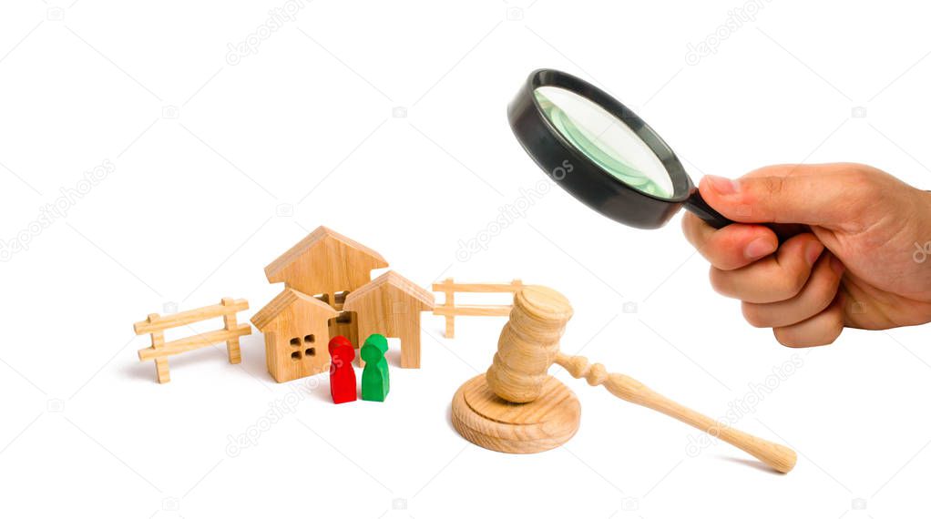Magnifying glass is looking at the Wooden apartment house with people, keys and a judge hammer on a white background. The concept of laws and regulations for tenants and owners of a building. .