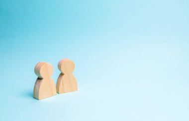 İki kişi yan yana ve konuş. İnsanların iki ahşap rakamlar mavi bir arka plan üzerinde bir konuşma yapmak. İletişim, buluşma yeri. Metin için yer. Minimalizm. Seçici odak