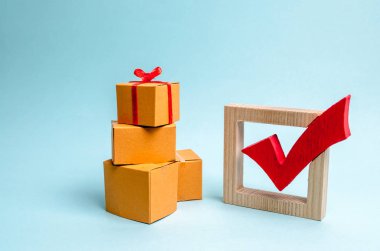 Bir hediye kutusu kutuları ve kırmızı onay işareti yığını üzerinde. Mükemmel bir hediye bulma kavramı. Alışveriş listesi. Sınırlı teklif. Satılık, büyük indirimler ve tatil öncesi heyecan. hedefe ulaşmak