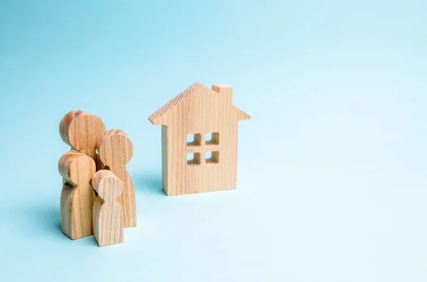 家族の立場に近い青色の背景に木造住宅 現実的なハウジングおよび若い家族連れやカップルのための家を購入するための住宅ローンの概念 プロパティ不動産の売買 — ストック写真