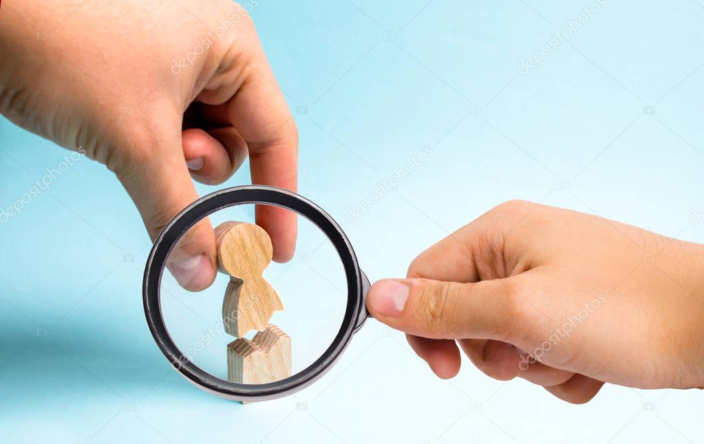 Magnifying glass is looking at the hand of the person collects a figure of the person together. Psychological assistance and support. Treatment of psychological and emotional trauma.