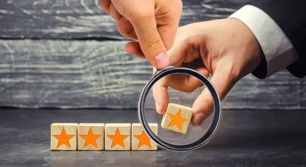 The businessman's hand holds the fifth star. Get the fifth star. The concept of the rating of hotels and restaurants, the evaluation of critics and visitors. Quality level, good service.