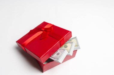 Beyaz zemin üzerine kırmızı hediye kutusu dolar. Ara tatil için bir hediye. Hediye sertifikası. Para en iyi hediyedir. Maliyet hediye. Sevgililer günü. Doğum günü. Para tasarrufu. Birikimi