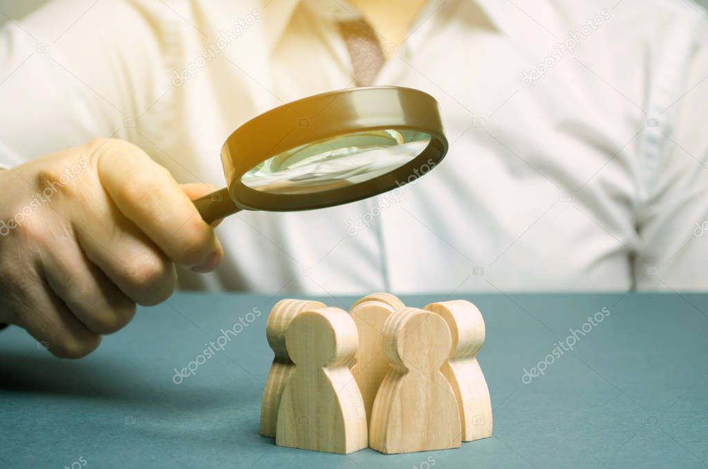 Business leader holding a magnifying glass over a team of workers. The concept of finding new employees. Teamliding. Team management. Hiring an employee. Human resources. Finding the employee. Scrum