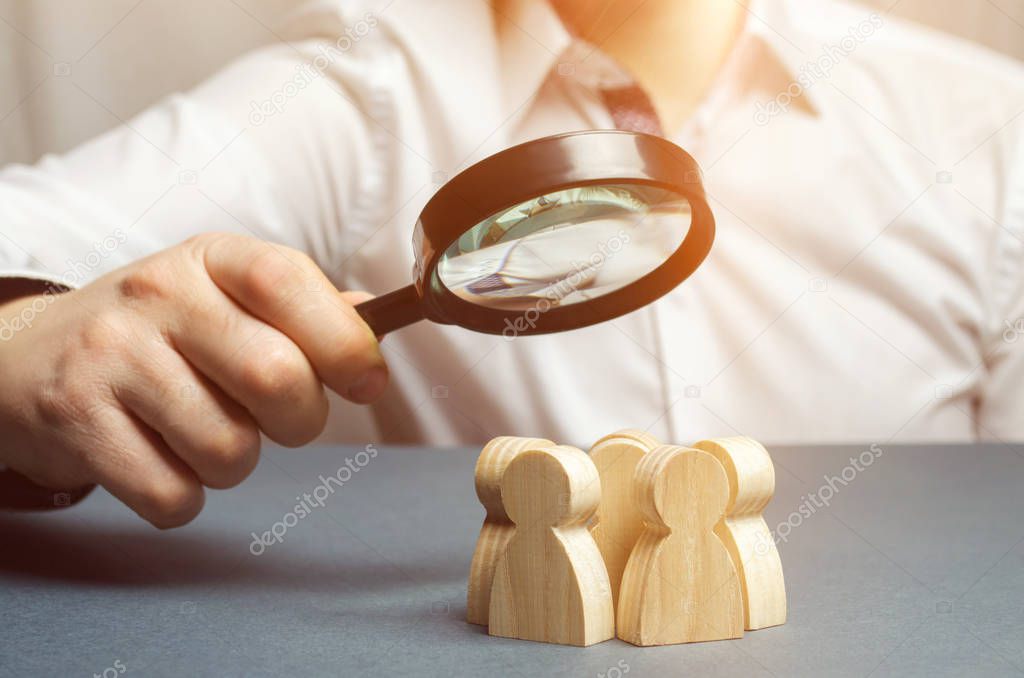 Business leader holding a magnifying glass over a team of workers. The concept of finding new employees. Teamliding. Team management. Hiring an employee. Human resources. Finding the employee. Scrum