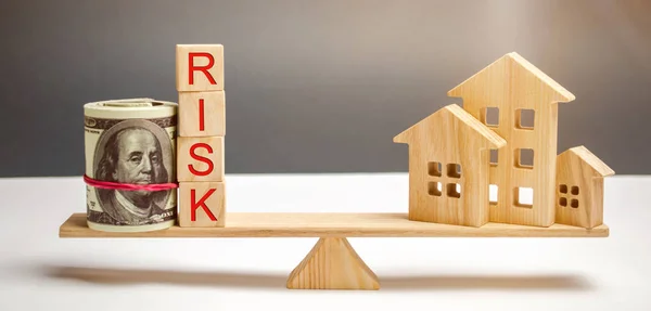 Money bag, blocks with the word Risk and a wooden house on the scales. The concept of losing money when investing in real estate. Risks of losing a home or housing for non-payment. Property insurance