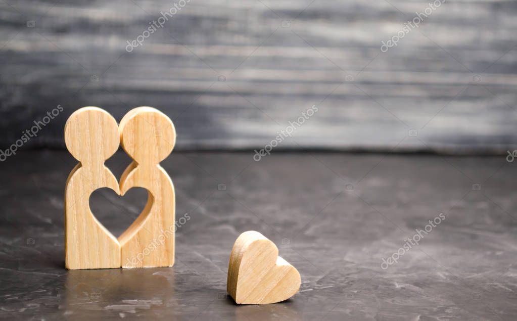 A miniature couple in love and a heart near them. The concept of family problems and loss of feelings for your loved one. Consultation family psychologist. Rupture / divorce. Selective focus
