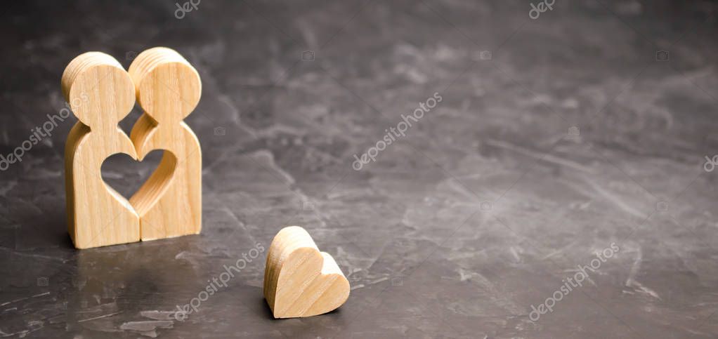 A miniature couple in love and a heart near them. The concept of family problems and loss of feelings for your loved one. Consultation family psychologist. Rupture / divorce. Selective focus