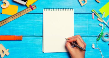 öğrenci not defterine kalem yazar. üst görünüm. düz yatıyordu. okul sırası, kırtasiye, eğitim konsepti, mavi arka plan, yaratıcı kaos, metin için alan, işaretleri, kalemler, not defterleri okul malzemeleri