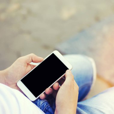 adam bir hareket eden smartphone tutarak ve ekrana bakarak. telefon bağımlılığı, sosyal ağlar. Internet üzerinde çalışma. mesajı yazın. güneşli bir gün. yakın çekim, metin için yer