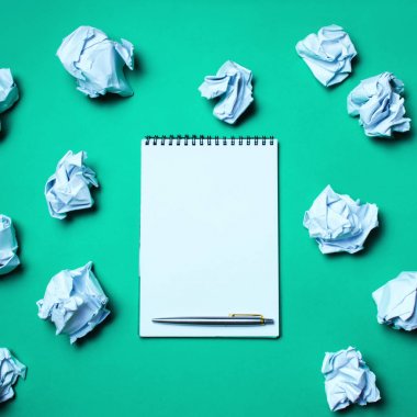 Beyaz defter kalem kağıt topları arasında yeşil bir arka plan ile. Getirici fikirleri, yeni fikirler icat kavramı. Her yerde Kağıt topları vardır. Kararları arama. Kötü fikir. İş