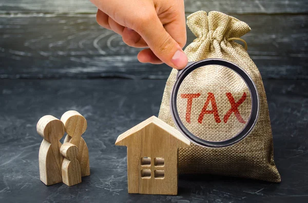 A bag with the word Tax and family stand near the house. Taxes on real estate, payment. Penalty, arrears. Register of taxpayers for property. Law-abiding, evasion of payment. Court law. Luxury tax. — Stock Photo, Image