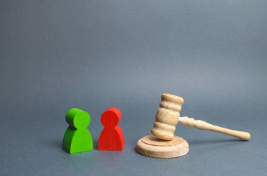 İnsanların iki figürü yargıcın toktunun yanında duruyor. Mahkemede uyuşmazlık çözümü, davacı ve davalı. Dava, çözüm ve anlaşmazlıkların çözümü. Yargı sistemi.