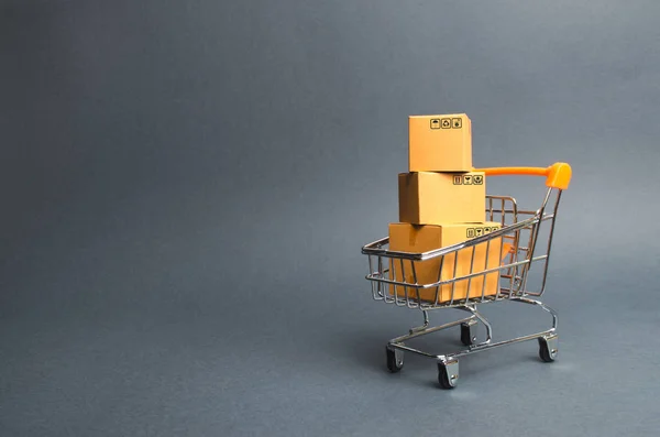 Une pile de boîtes en carton dans un chariot de supermarché. concept de shopping dans la boutique en ligne. Commerce électronique, vente et vente de marchandises par le biais de plateformes de trading en ligne. La société de consommation. Pouvoir d'achat — Photo