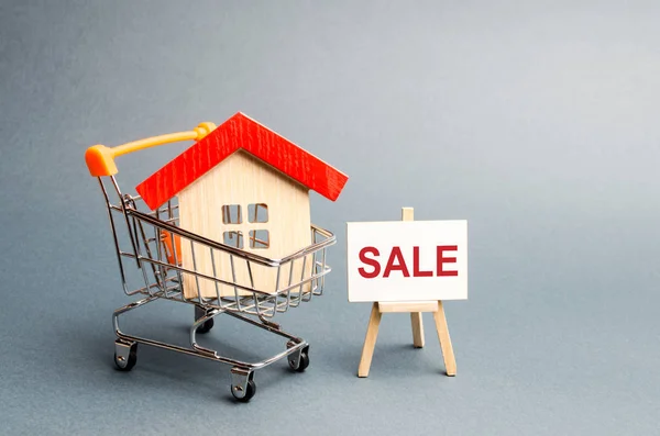 Supermarket cart with houses and a Sale Poster. The concept of selling a home, real estate services or buying from the owner. Buying and selling real estate, property, apartments. Selective focus