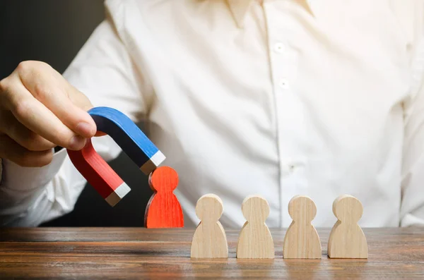 Affärsmannen drar en röd figur från laget med en magnet. Begreppet giftig och icke-kompetent arbetstagare. Öka teamets effektivitet och produktivitet. Leader driver verksamheten och bildar ett team. — Stockfoto