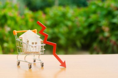 Bir ticaret sepeti ve kırmızı ok aşağı iki ahşap evler. düşen emlak piyasası. İpotek faizinde indirim. Emlak fiyatları ve dairelerde bir düşüş. Mortgage kredileri düşük faiz oranları.