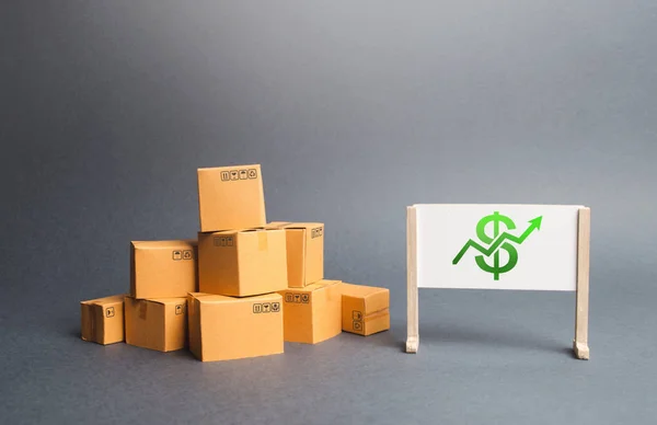 Karton kutular ve dolar işareti ve yeşil ok ile beyaz tahta bir yığın. Üretimin büyüme hızı. Artan tüketici talebi. Mal satışından elde edilen gelirin artması. Fiyat artışı. — Stok fotoğraf
