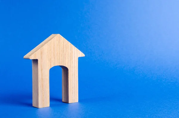 Ξύλινο σχήμα ενός σπιτιού με μια μεγάλη πόρτα σε μπλε φόντο. έννοια της αγοράς και πώλησης ακινήτων, ενοικίου, επενδύσεων. Σπίτι, προσιτή στέγαση, οικιστικό κτίριο. Οικοδομικά κτίρια. — Φωτογραφία Αρχείου