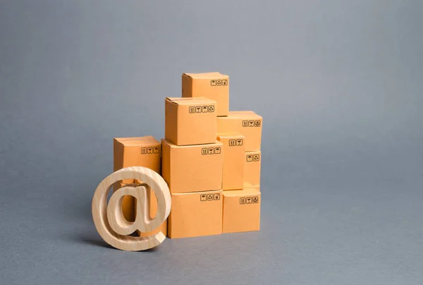 Pila de cajas de cartón y el símbolo de correo electrónico comercial AT. Comercio electrónico. ventas de bienes a través de plataformas comerciales en línea. compras en línea. desarrollo del comercio de redes de Internet, servicios de publicidad . — Foto de Stock