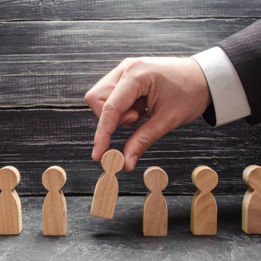 Elini bir işadamı bir adam ahşap bir rakam tutuyor. İşe alma ve işçiler, promosyon ateş arama kavramı. İş taktik ve strateji, yönetim, işletme yönetimi.