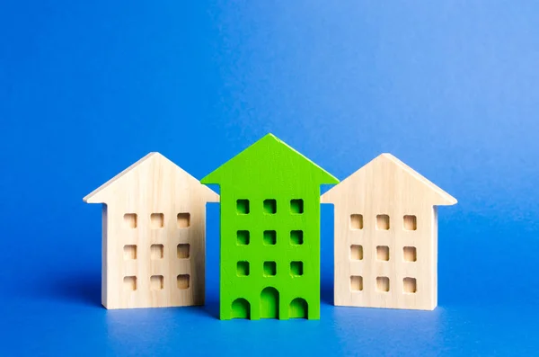 Die grüne Figur eines Wohnhauses ragt zwischen den übrigen Häusern hervor. Suche nach der besten Option für den Kauf einer Wohnung unter den Möglichkeiten. hohe Qualität und günstige Lage der Immobilie. — Stockfoto
