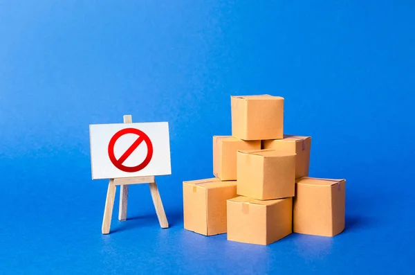 Een stapel stapel kartonnen dozen en een bordje met rood symbool Nee. Beperking van de invoer van goederen, bedrijfseigen. Embargo, handelsoorlogen. Onvermogen om producten te verkopen, verbod op de import. — Stockfoto