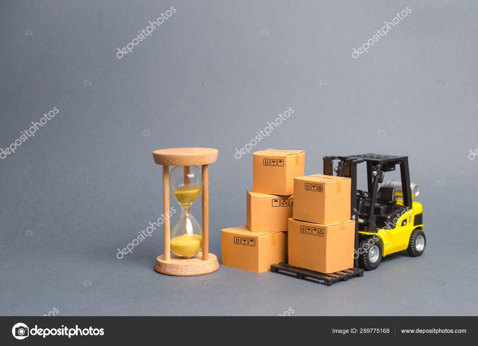 Carretilla elevadora amarilla de cartón y un reloj de arena. Concepto de entrega
