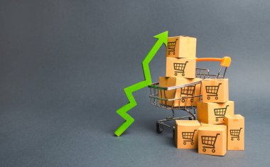 Ticaret arabaları ve yeşil yukarı ok bir desen ile karton kutular ile alışveriş sepeti. Satışların hızını, malların üretimini artırın. Tüketici duygusunda iyileştirme. Gelir artışı için strateji