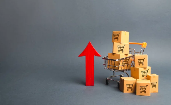 トレーディングカートと赤い上矢印のパターンを持つ段ボール箱とショッピングカート。成長卸売と小売。消費者マインドの改善、経済成長物価の上昇、物価上昇 — ストック写真